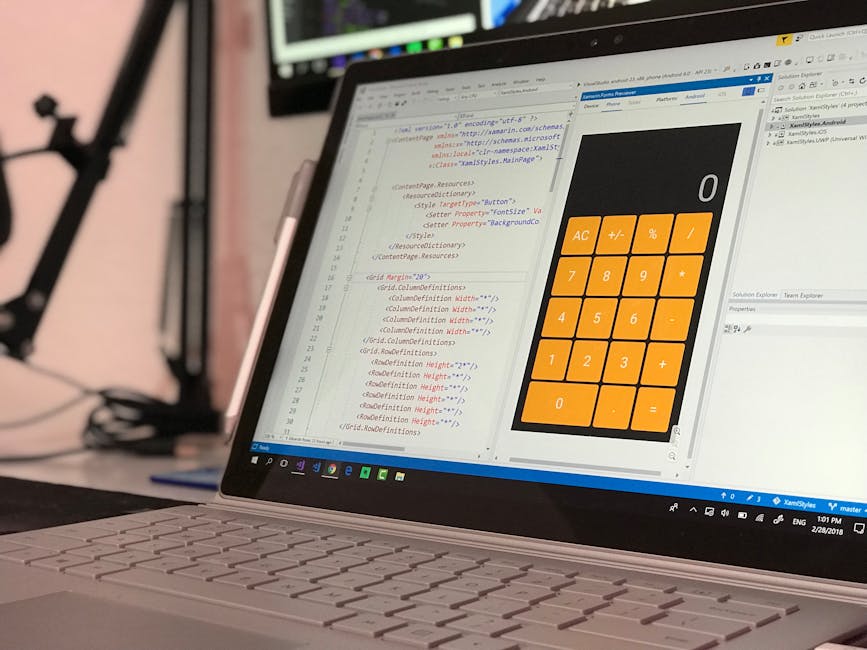 A person seated at a desk during a house removal planning session, working with a laptop that displays a code or data on the screen. The individual is using a mouse with their right hand and holding a